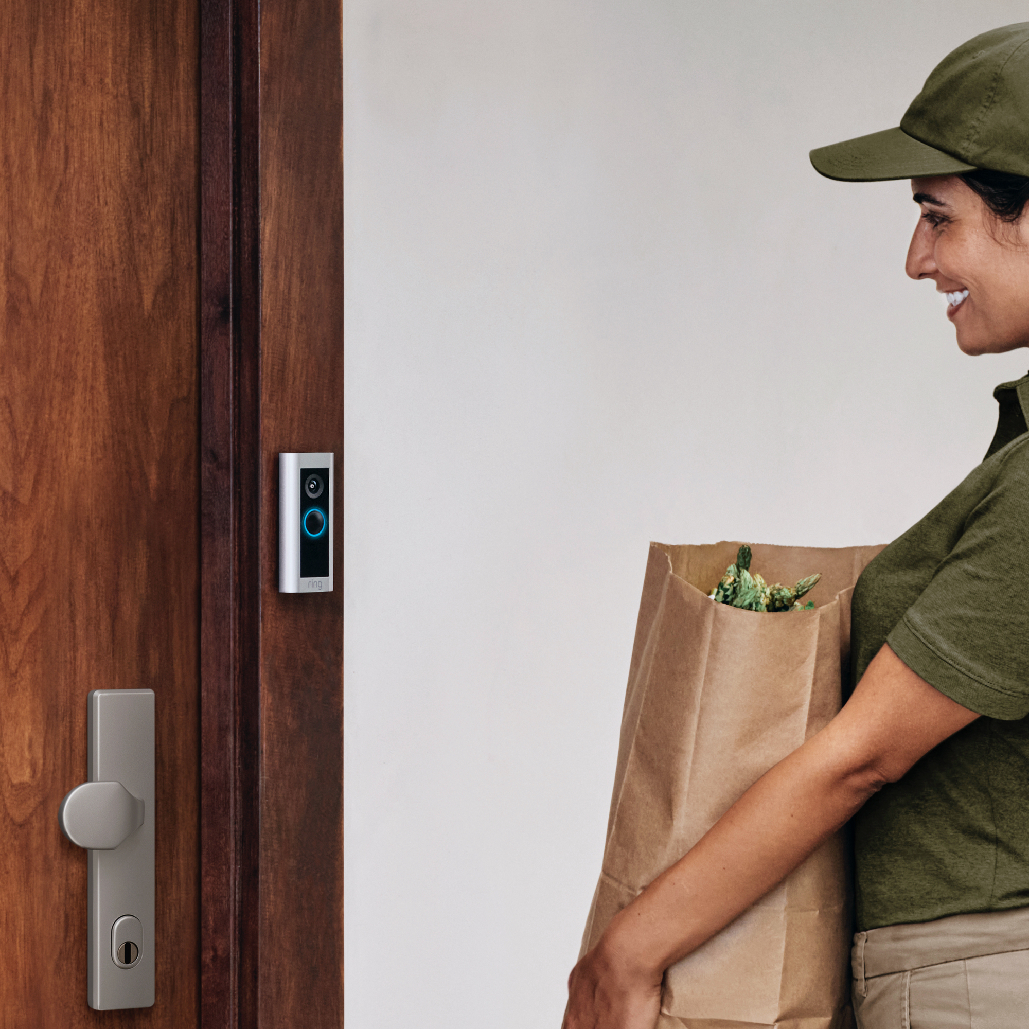 Livreur tenant un sac d'épicerie à côté d'une sonnette sur une porte en bois.