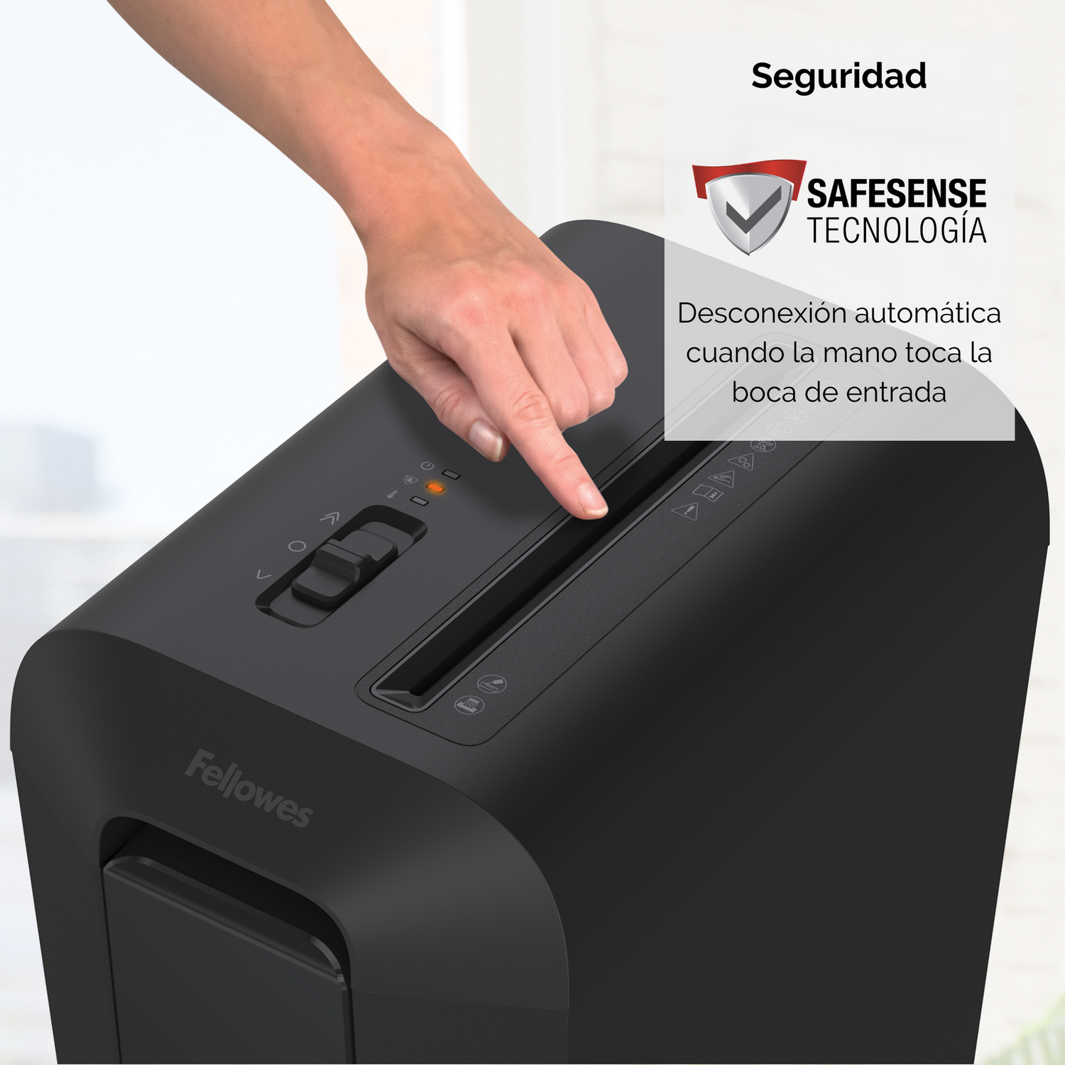Una mano presiona la ranura de la trituradora de papel. La trituradora es negra, con una función de seguridad.