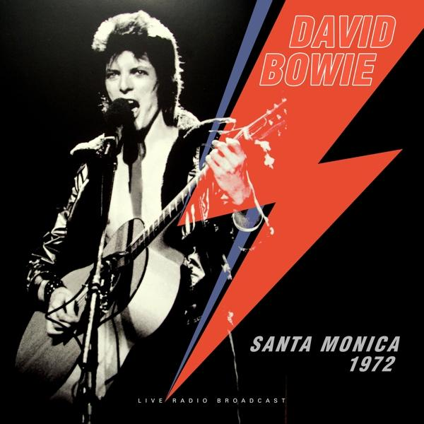 David Bowie 1972-ben élőben lép fel, zakót visel és gitározik.