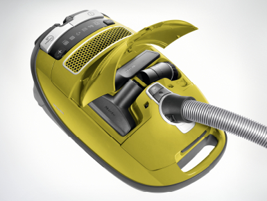 Aspirateur jaune avec accessoires et compartiment ouvert.
