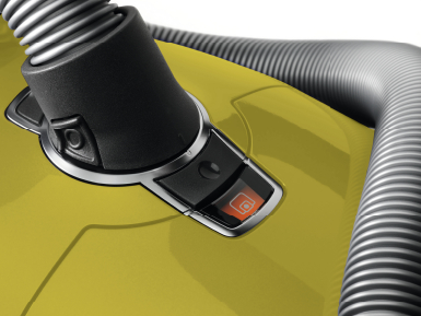 Gros plan d'un aspirateur jaune. Montre le bouton d'alimentation avec un voyant orange.