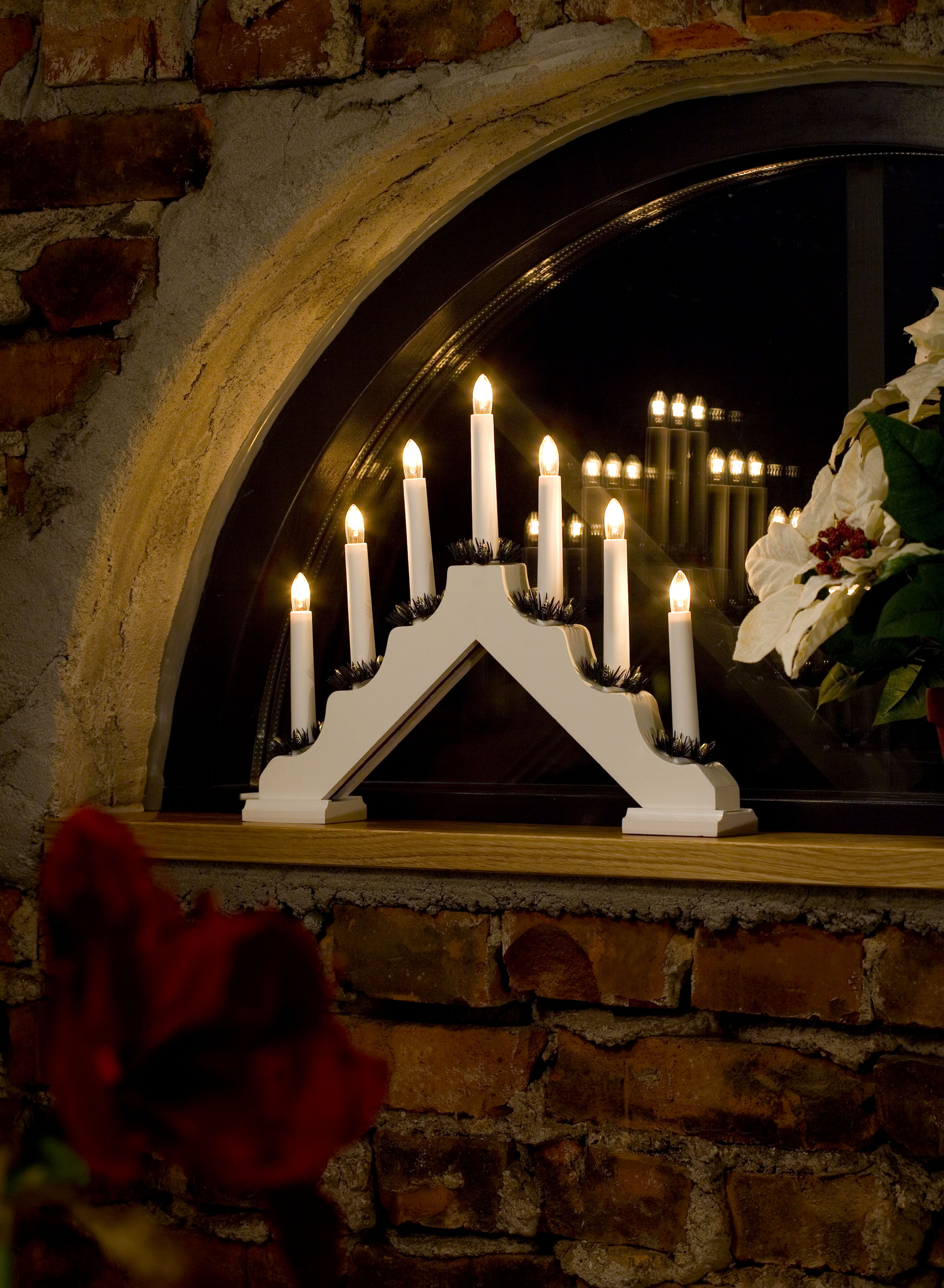 Eine Weihnachtsdekoration mit Kerzen und einem weißen Bogen steht in einem Fenster.