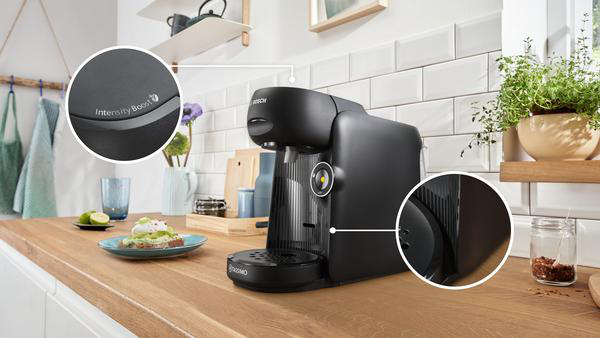 Eine schwarze Kaffeemaschine auf einer Holz-Arbeitsplatte, mit einer Nahaufnahme der Bedienelemente.