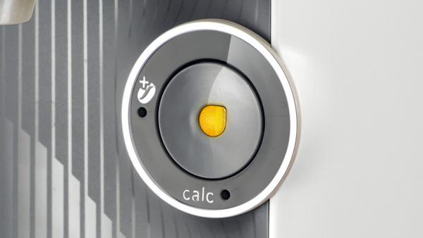 Nahaufnahme eines grauen, kreisförmigen Bedienfelds. Hat eine Taste und das Wort 'calc'.