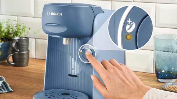 Eine Hand drückt eine Taste an einer blauen Bosch Kaffeemaschine, Nahaufnahme.