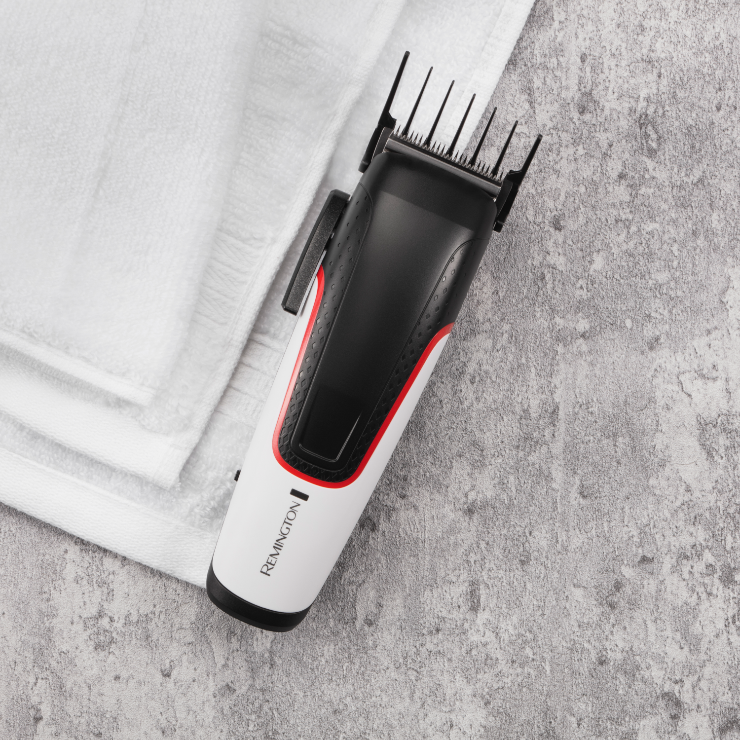 Black and white hair clipper on a white towel on a grey surface.