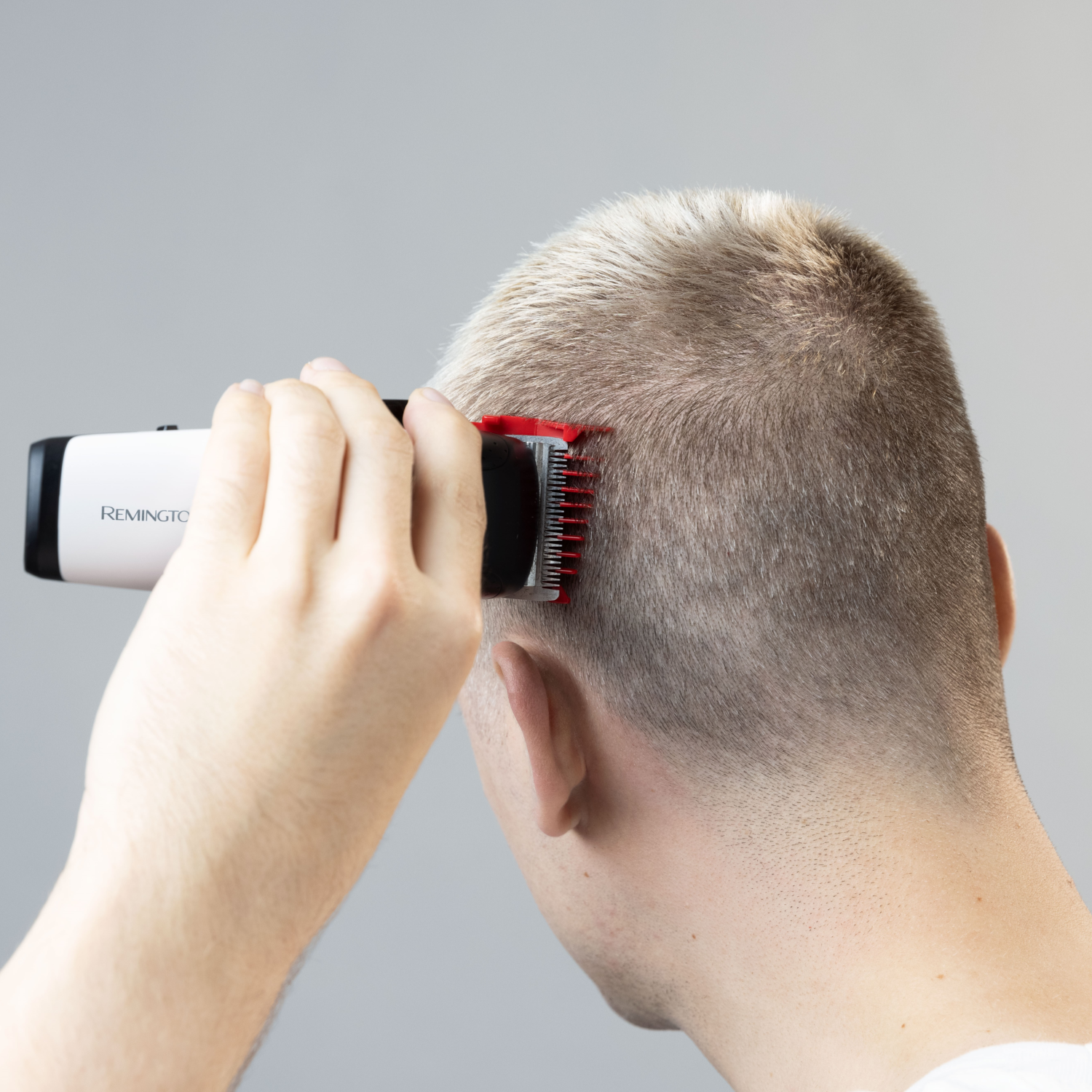 A person is cutting their hair with a Remington hair clipper.