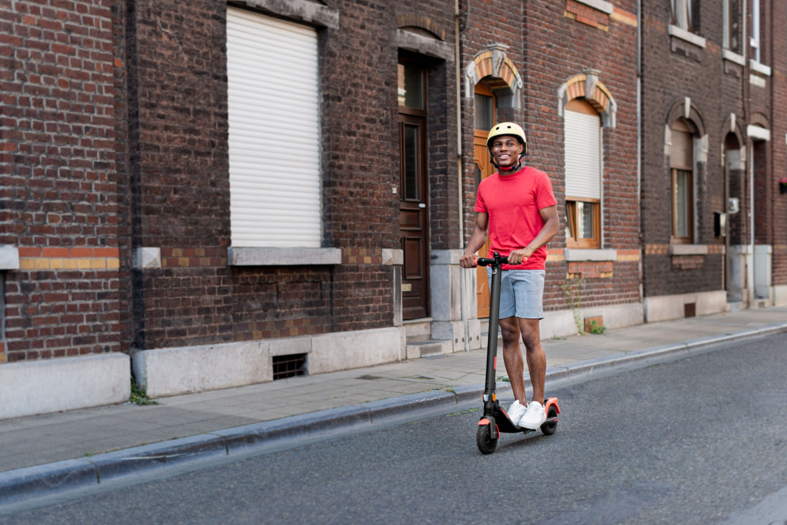 Adam sokakta scooter sürüyor.