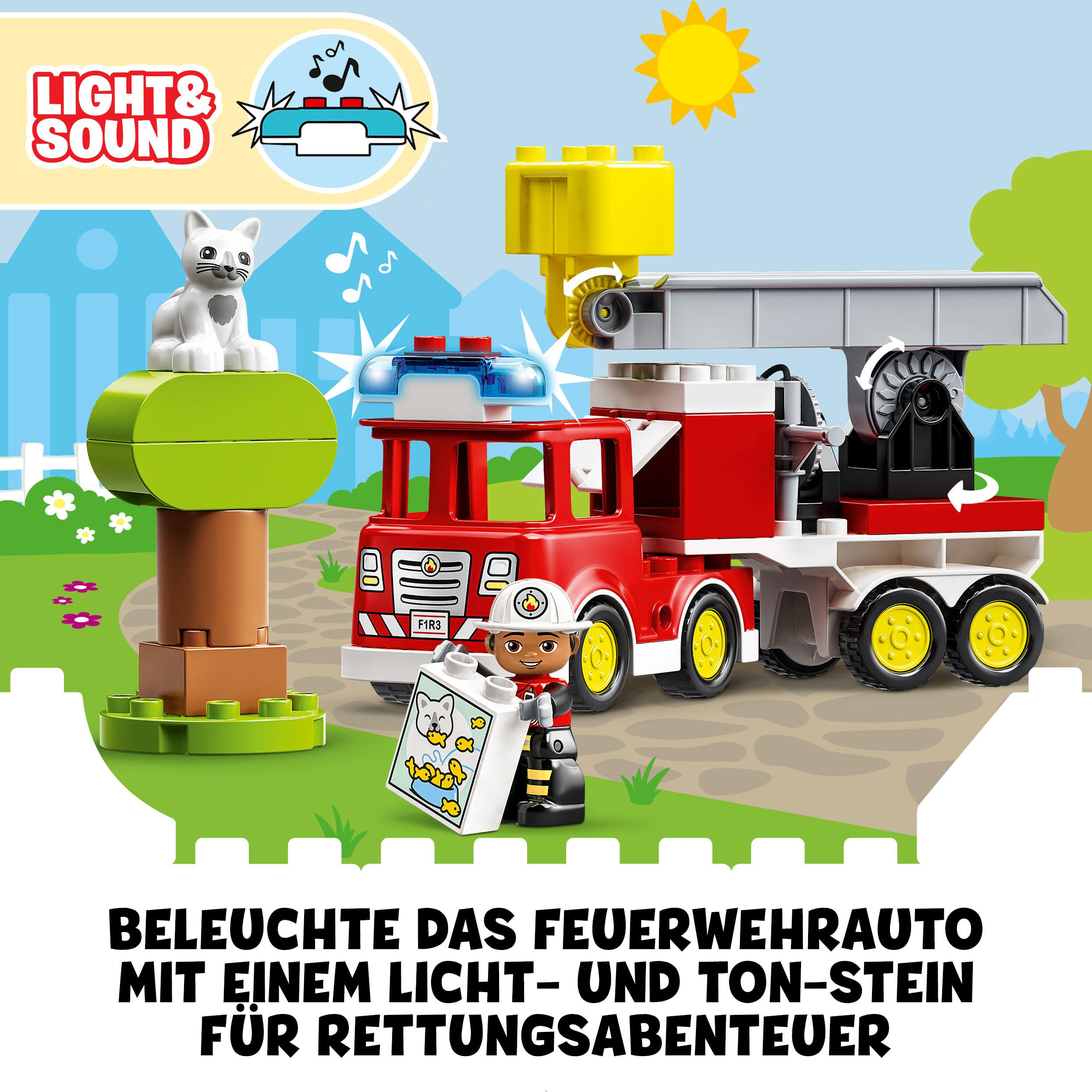 Spielzeug-Feuerwehr mit Feuerwehrmann und Katze. Helle Farben und Soundeffekte. Hintergrund mit sonnigem Tag.