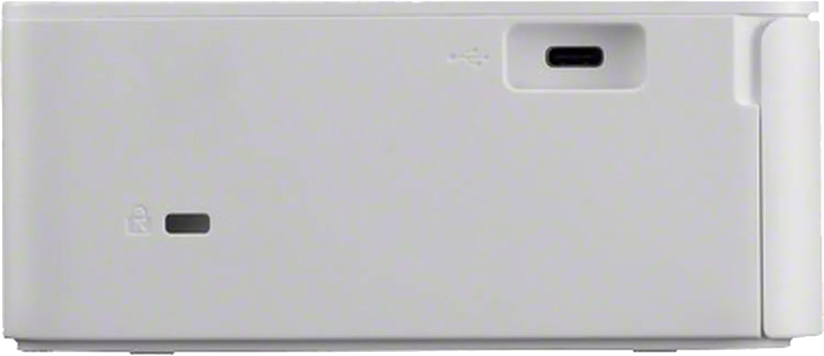 Fehér eszköz, oldalsó nézet, USB porttal és zár szimbólummal.