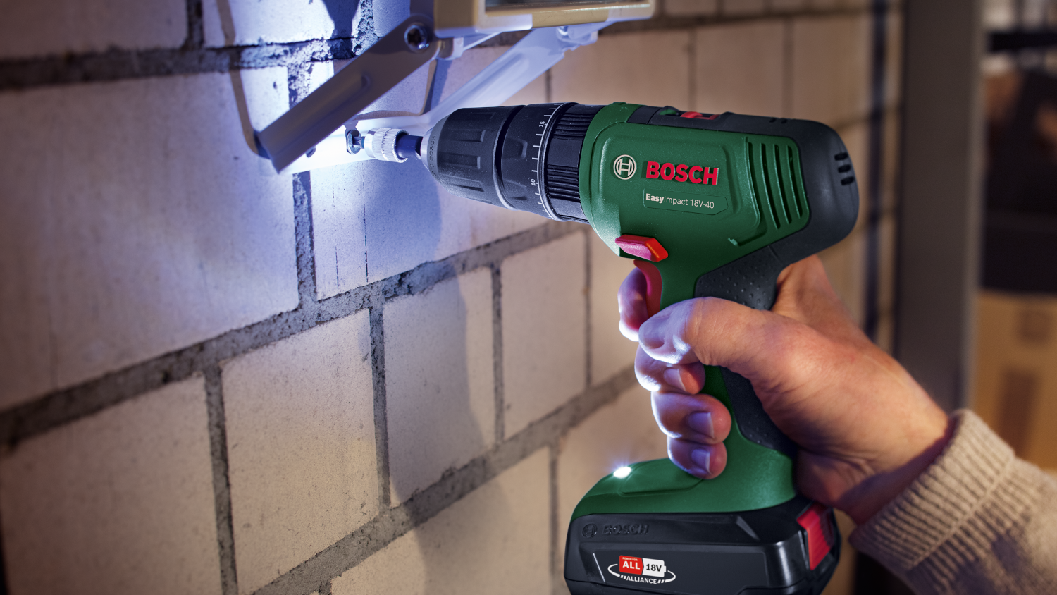 Egy személy egy zöld-fekete Bosch EasyImpact 18V-40 fúrót használ.