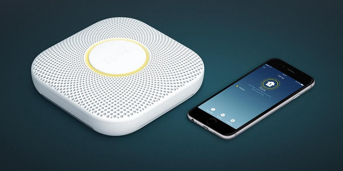Un détecteur de fumée Nest blanc et un smartphone affichant une interface d'application.