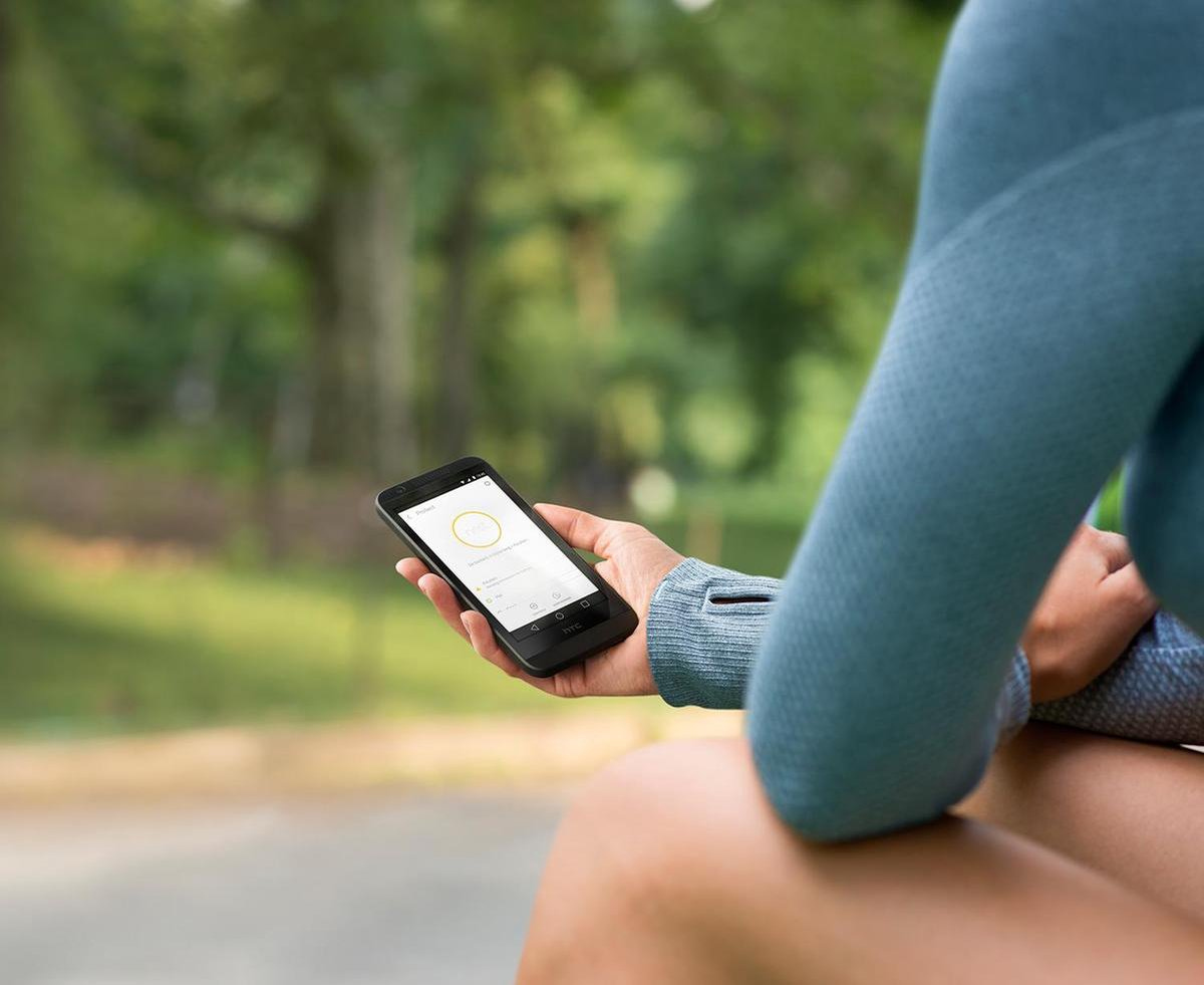 De hand van een persoon die een zwarte smartphone vasthoudt met een gele cirkel op het scherm.