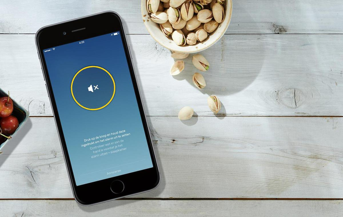 Smartphone met mute-icoon en pistachenoten op houten oppervlak.