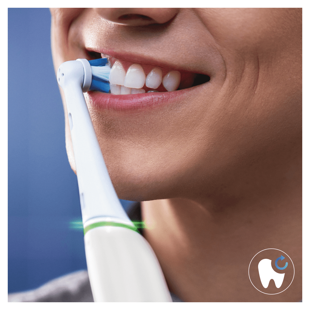 Una persona cepillándose los dientes con un cepillo de dientes eléctrico.