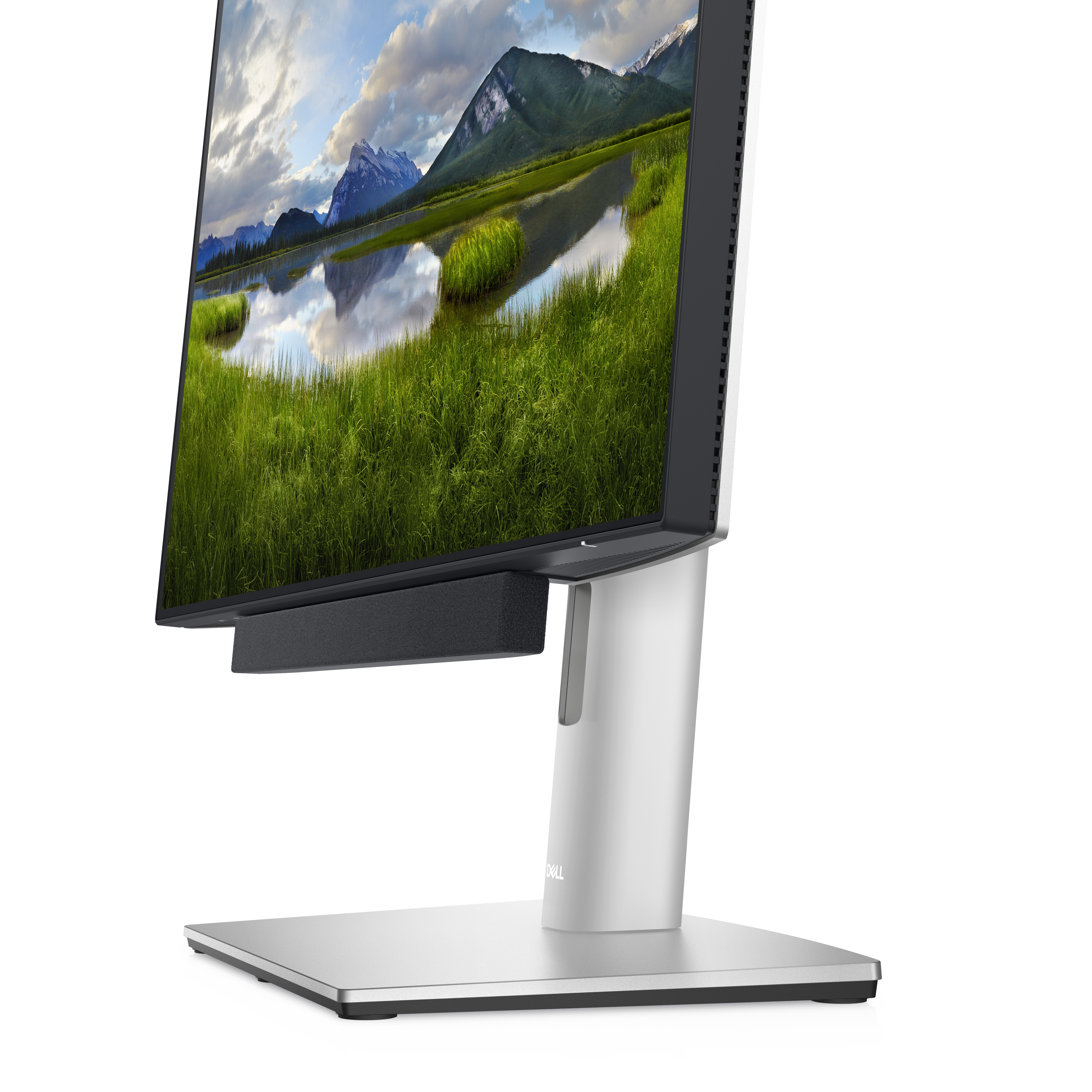 Ein Computermonitor mit einer Landschaft mit Bergen, einem See und grünem Gras. Der Monitor steht auf einem silbernen Ständer.