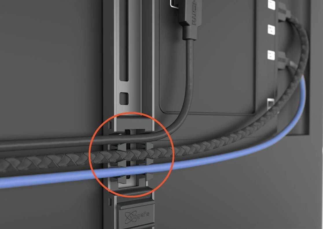Câbles connectés à un téléviseur, maintenus par un support, avec un organiseur de câbles.