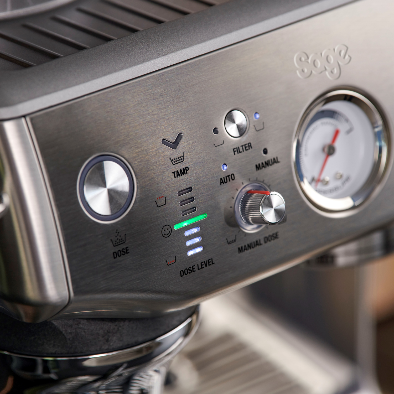 Close-up van een zilveren espressomachine met een meter en bedieningspaneel.