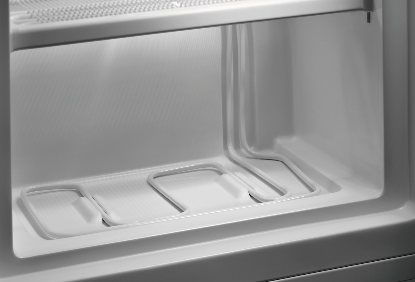 Inside of a white refrigerator, showing shelves and cooling elements.