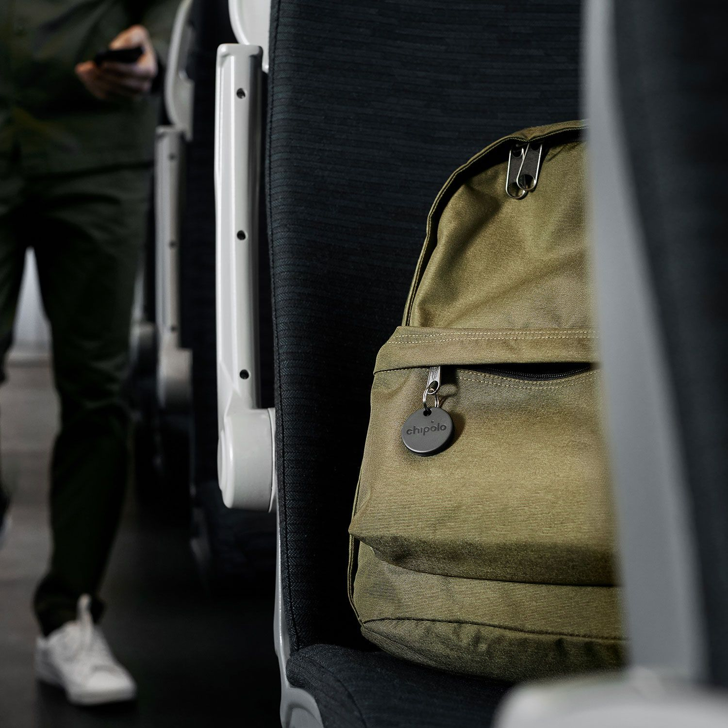 Ein Rucksack mit einem Chipolo-Anhänger auf einem Sitz in einem öffentlichen Verkehrsmittel.