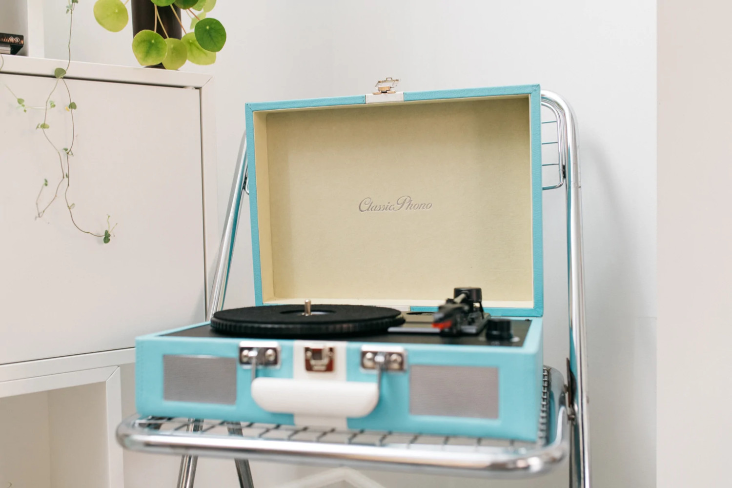 Un tourne-disque vintage bleu, ouvert, avec un disque sur le plateau tournant.