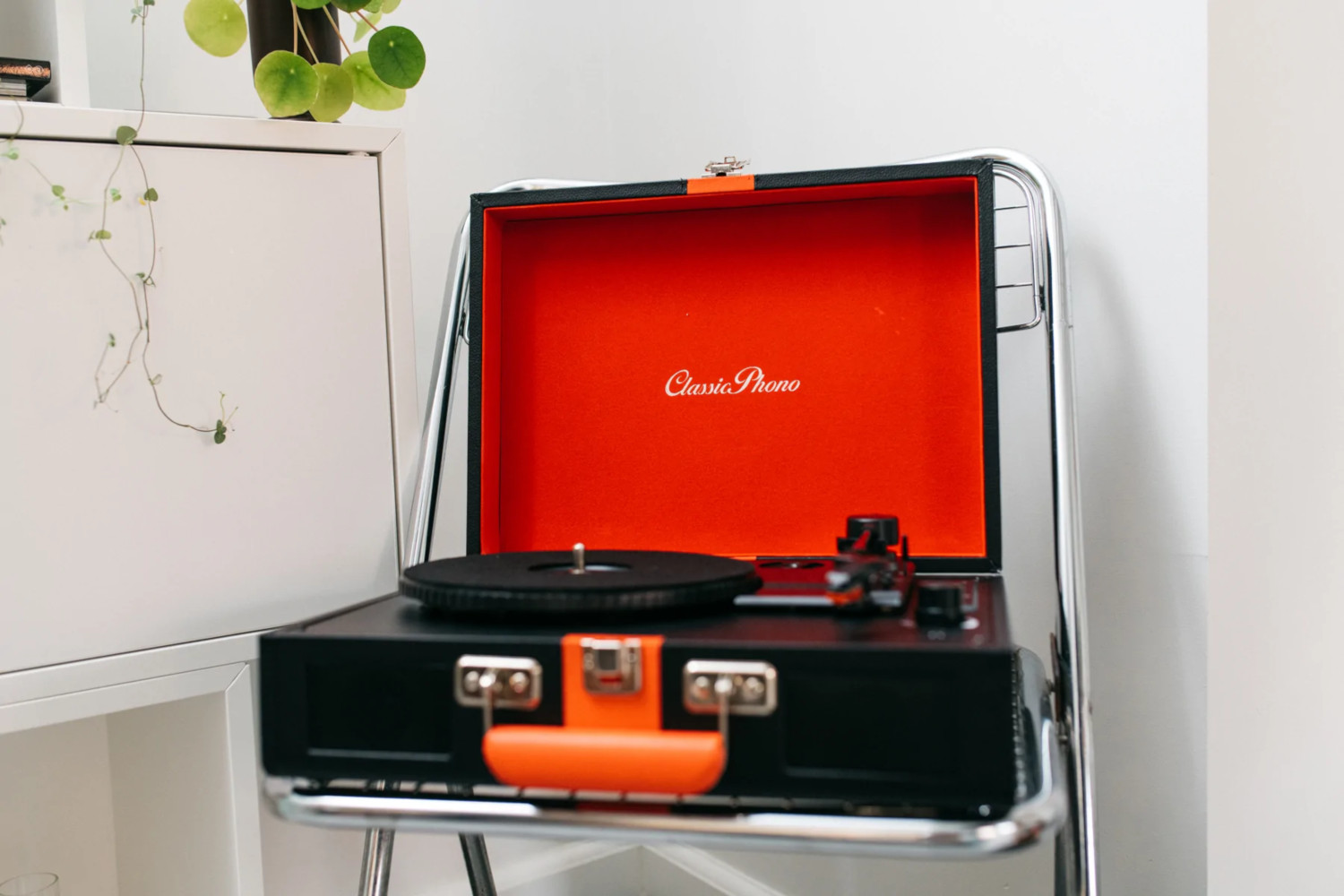 Un tourne-disque vintage dans un étui noir avec un intérieur orange.