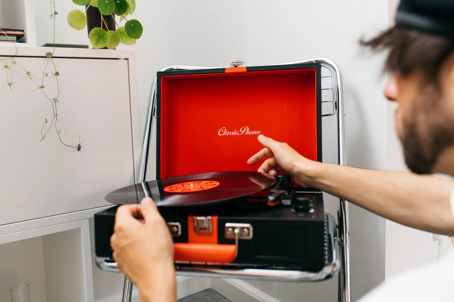 Une personne place un disque vinyle sur une platine rétro noire et rouge.