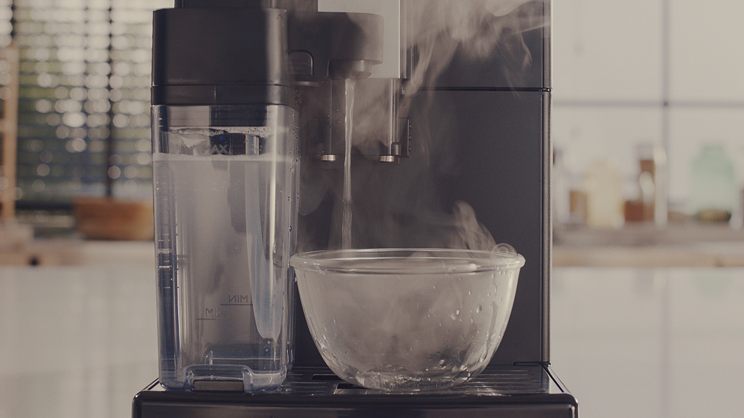 Koffiezetapparaat dat water stoomt in een glazen kom. Doorzichtige watercontainer zichtbaar.