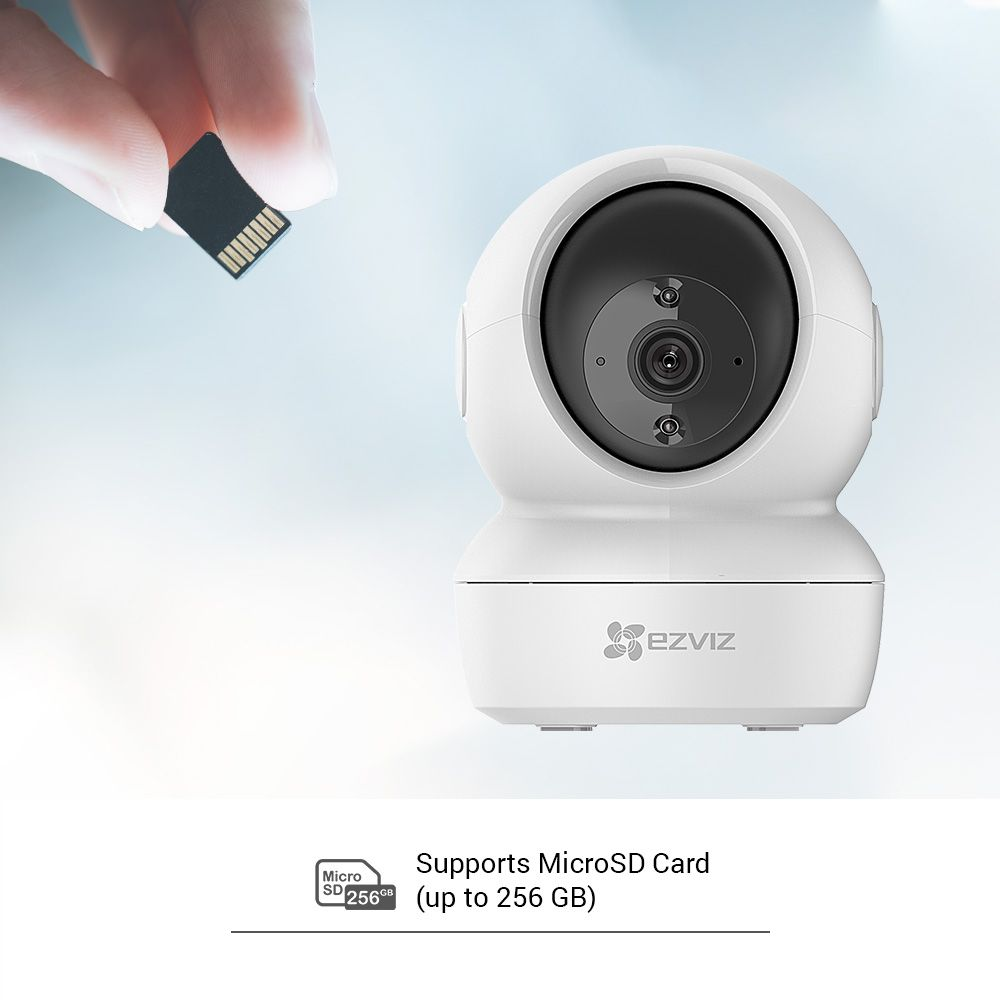 Caméra de sécurité blanche avec une carte micro SD insérée à la main.