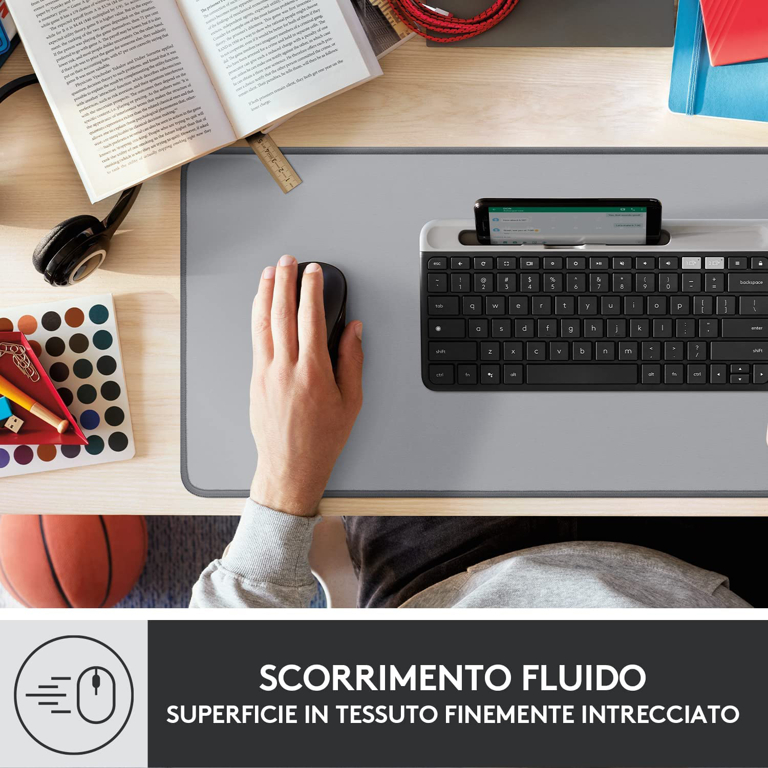 Una mano su un mouse, una tastiera e un telefono, con uno sfondo sfocato di un'impostazione da scrivania.
