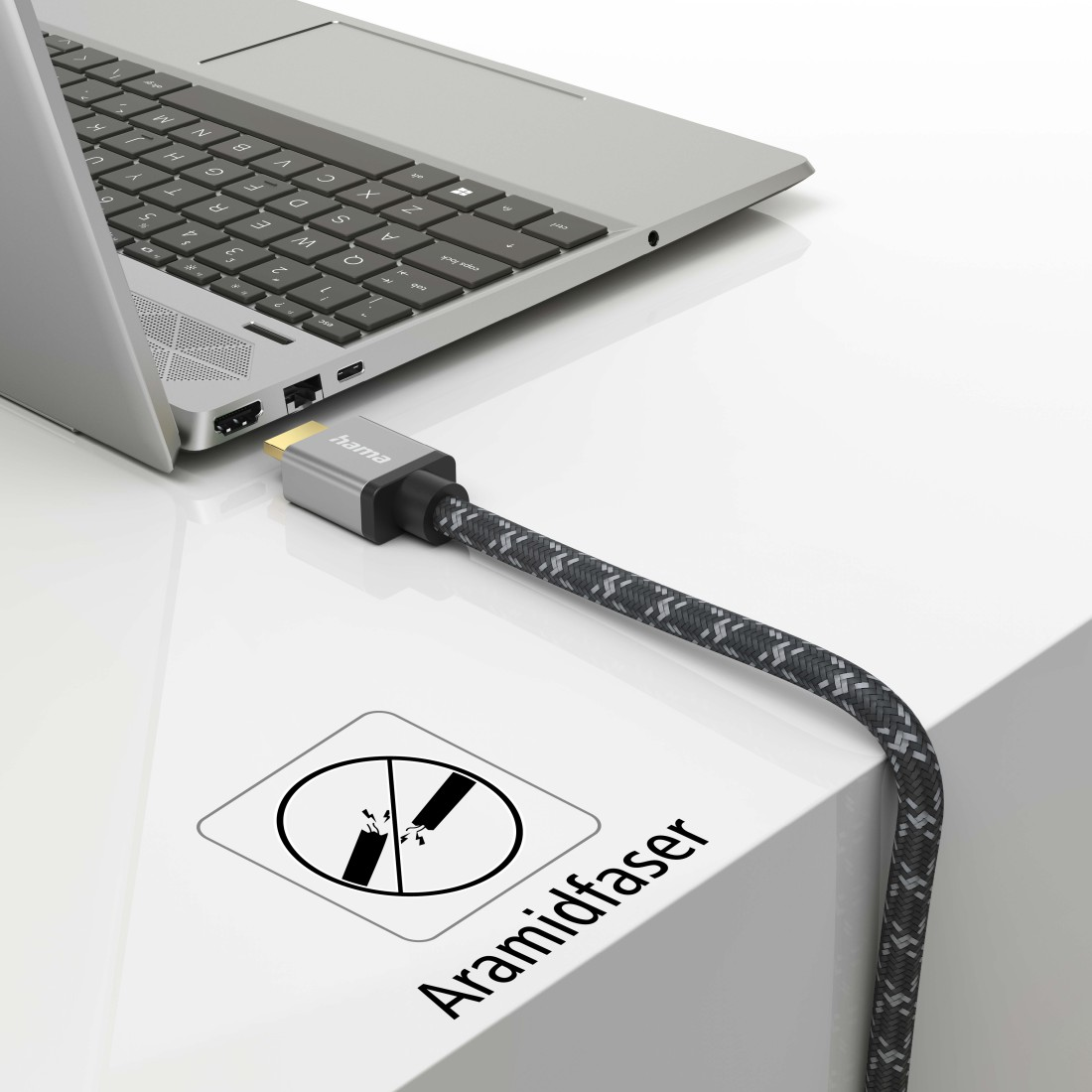 Un ordinateur portable connecté à un câble HDMI. Le câble est connecté à une surface blanche. Il y a un symbole sur la surface.