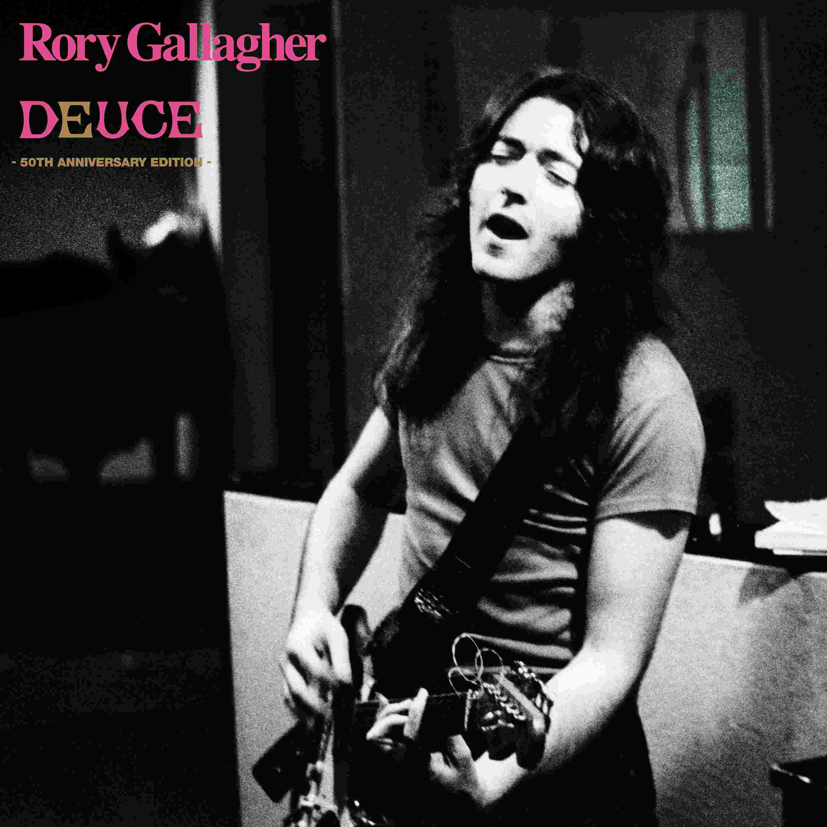 Rory Gallagher spielt Gitarre und singt auf der Bühne, Schwarzweißbild.