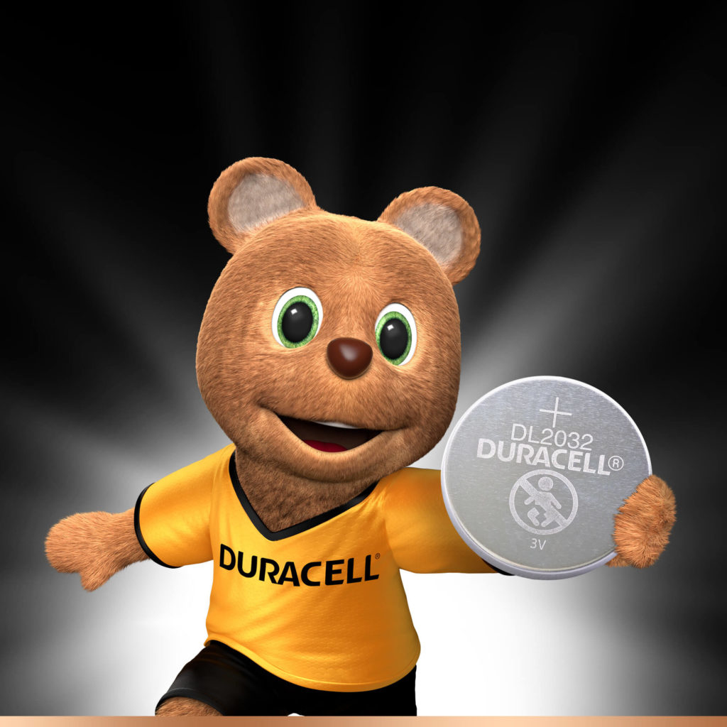 Bärenmaskottchen mit gelbem Hemd, hält eine silberne Duracell-Batterie.