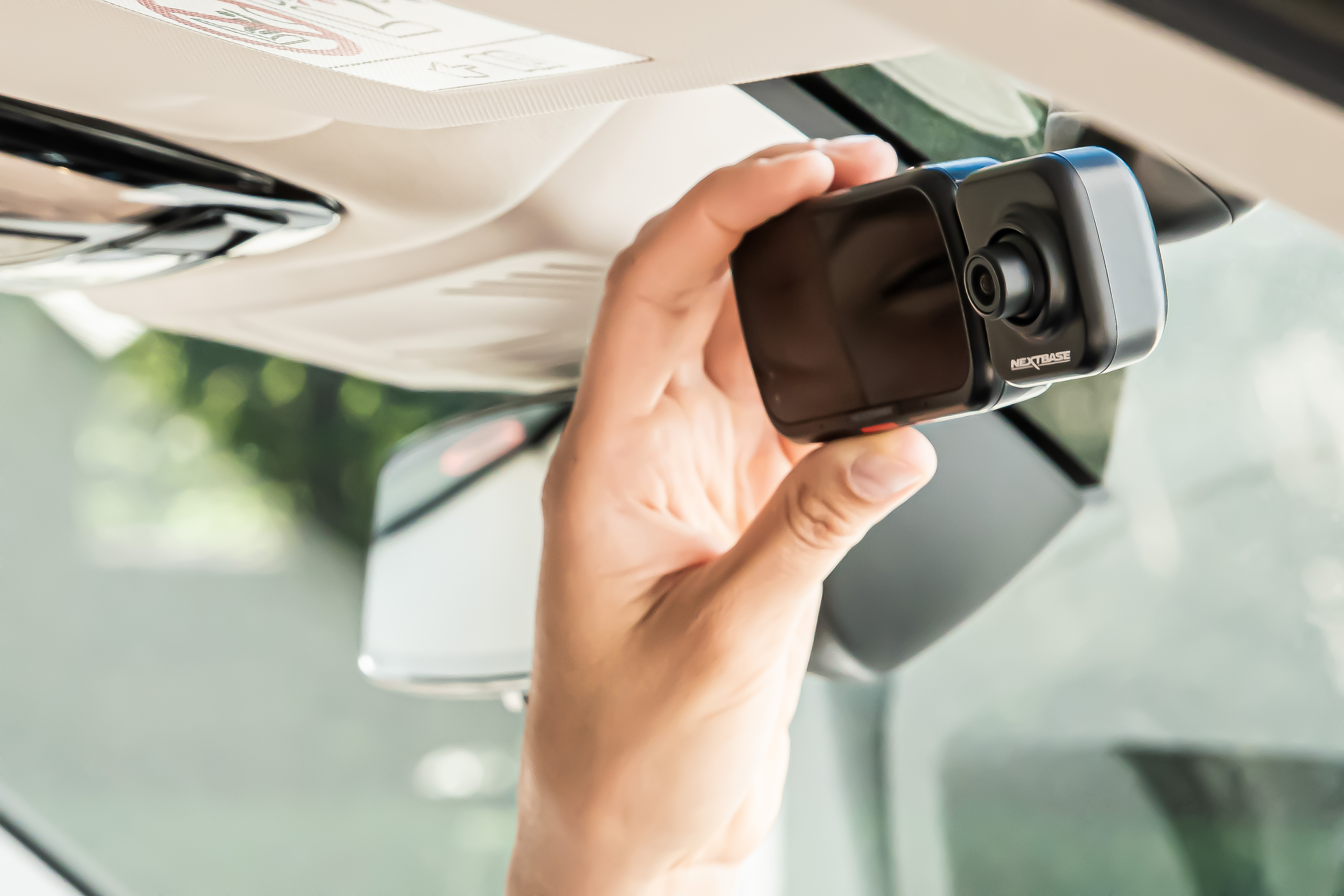 Hand installiert eine Dashcam im Auto, in der Nähe des Rückspiegels.