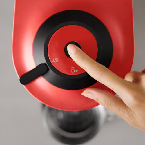 Finger drückt roten Knopf an einer Maschine.