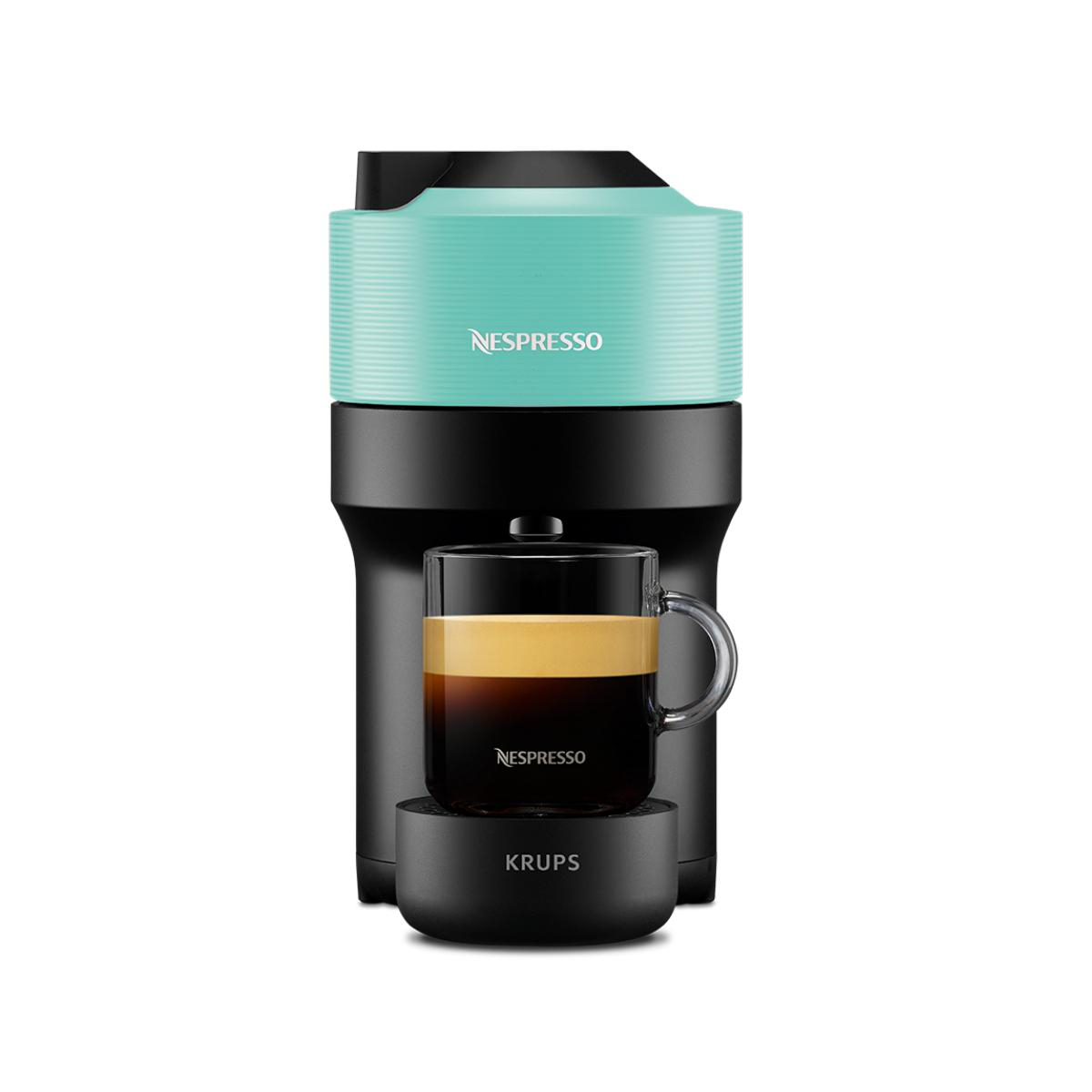 Nespresso Kaffeemaschine mit einer Tasse darunter. Die Maschine hat einen türkisfarbenen Deckel und einen schwarzen Sockel.