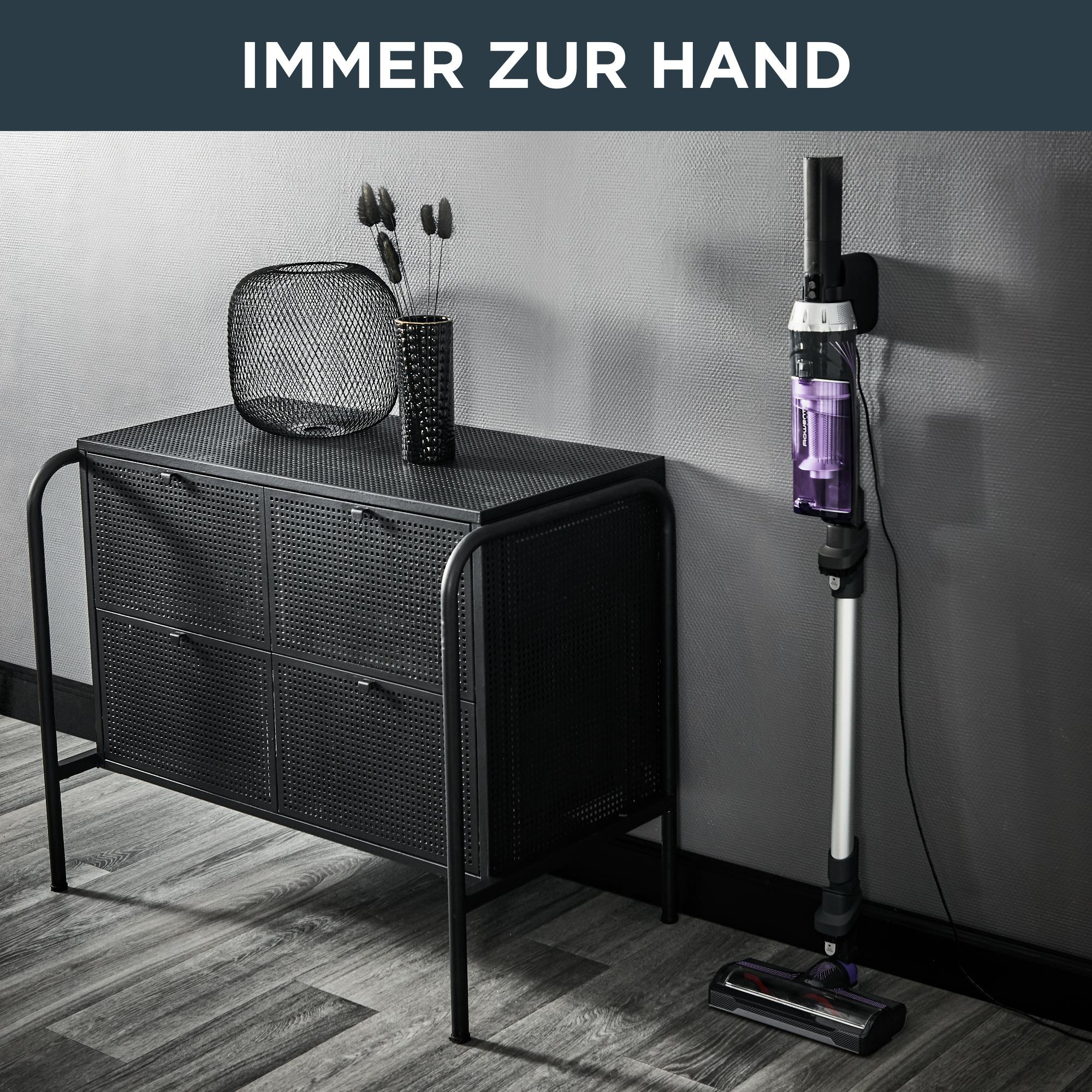 Ein schwarzer Schrank mit Vase und Dekoration. Ein Staubsauger ist an der Wand montiert.