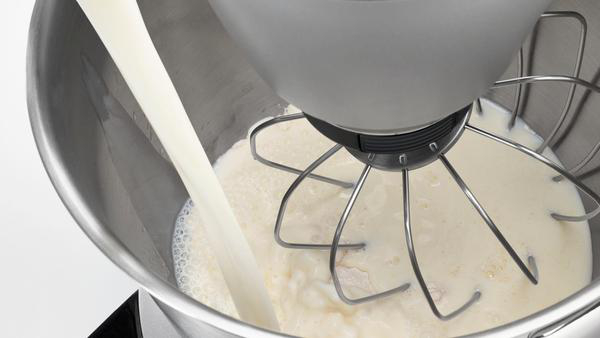 Milch wird in eine Edelstahl-Rührschüssel mit Schneebesen-Aufsatz gegossen.