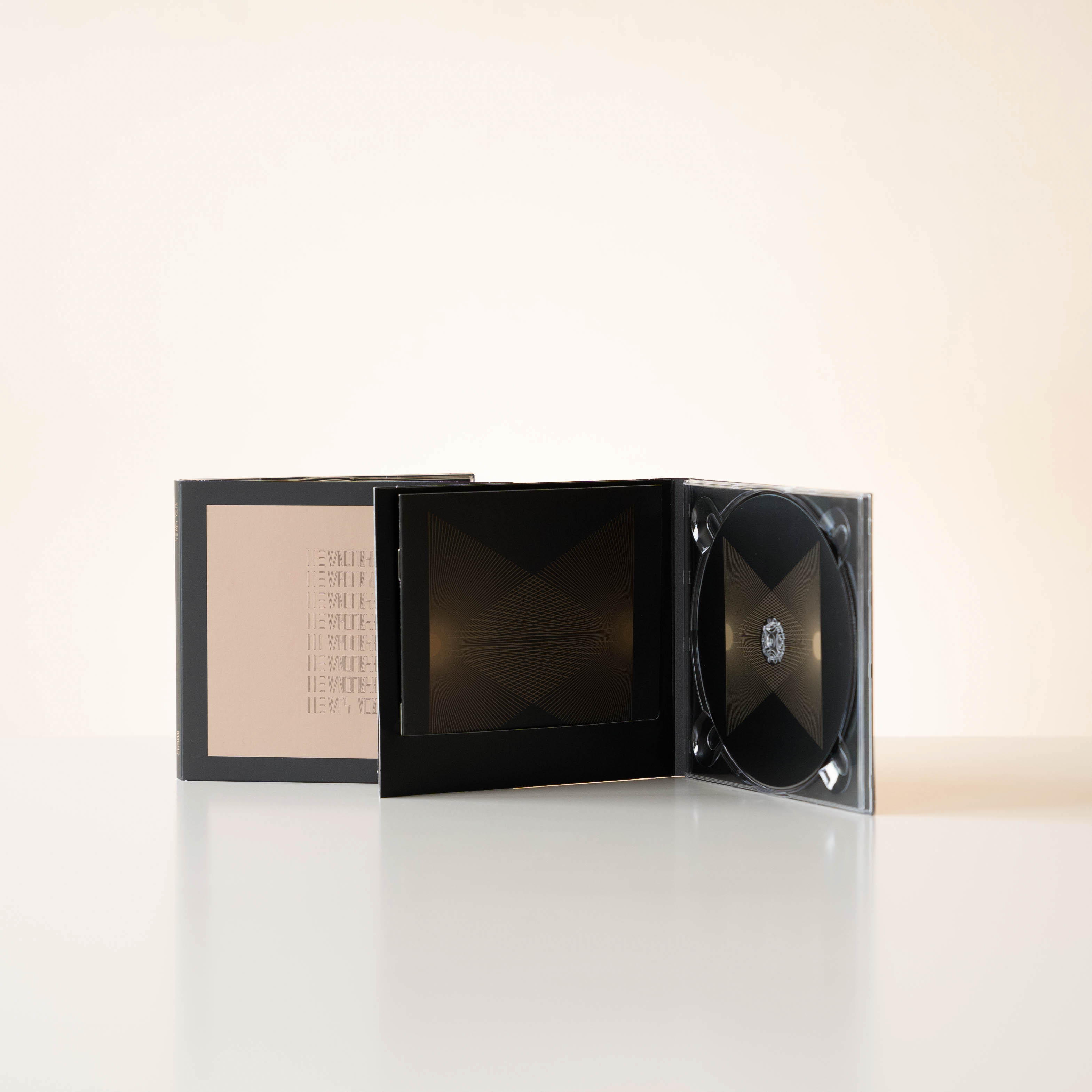 Eine schwarze CD-Hülle mit goldenem Design. Die CD-Hülle ist geöffnet, mit einer CD darin, auf hellem Hintergrund.