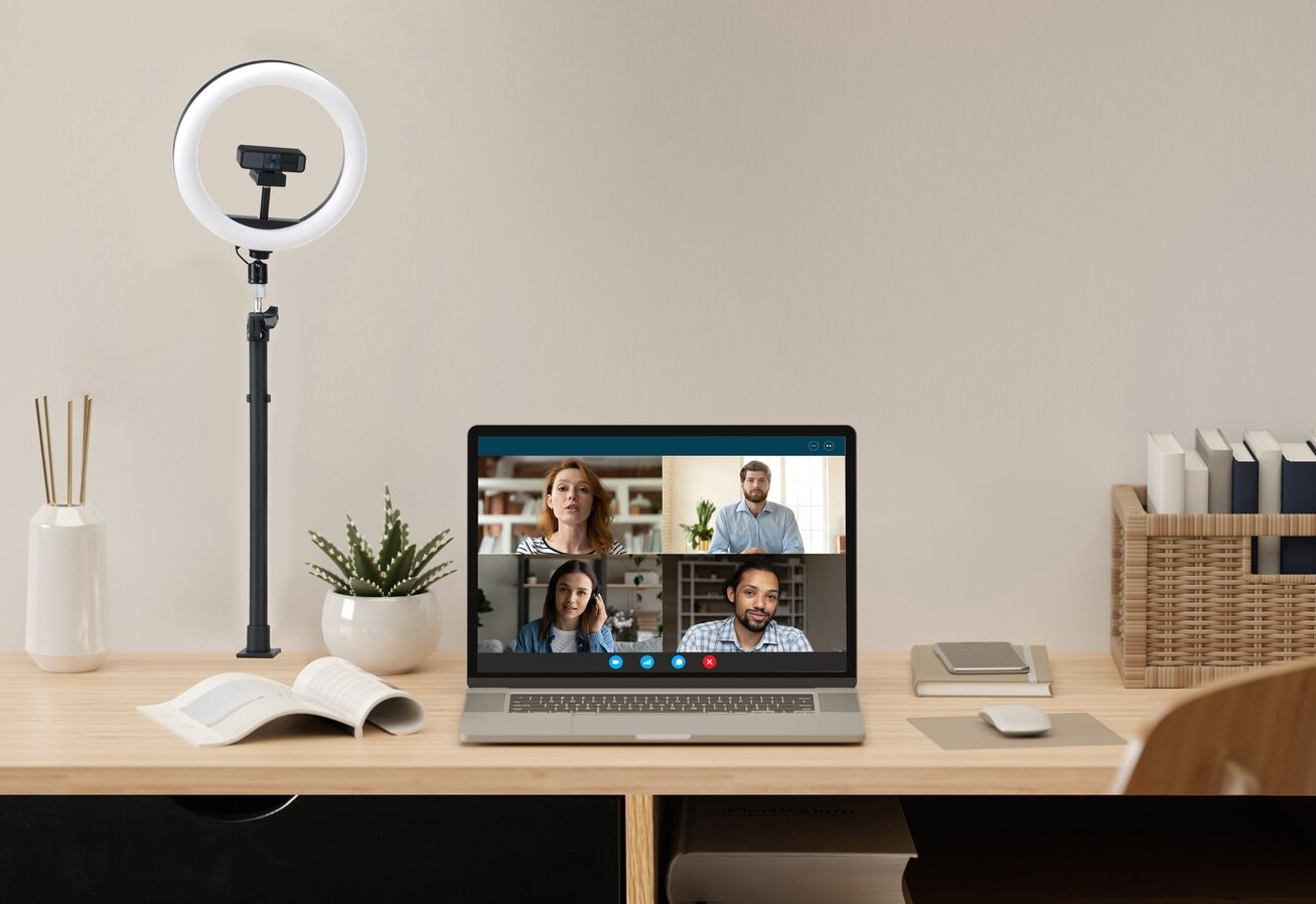 Laptop egy asztalon gyűrű fénnyel és videóhívással, irodaszerekkel együtt.
