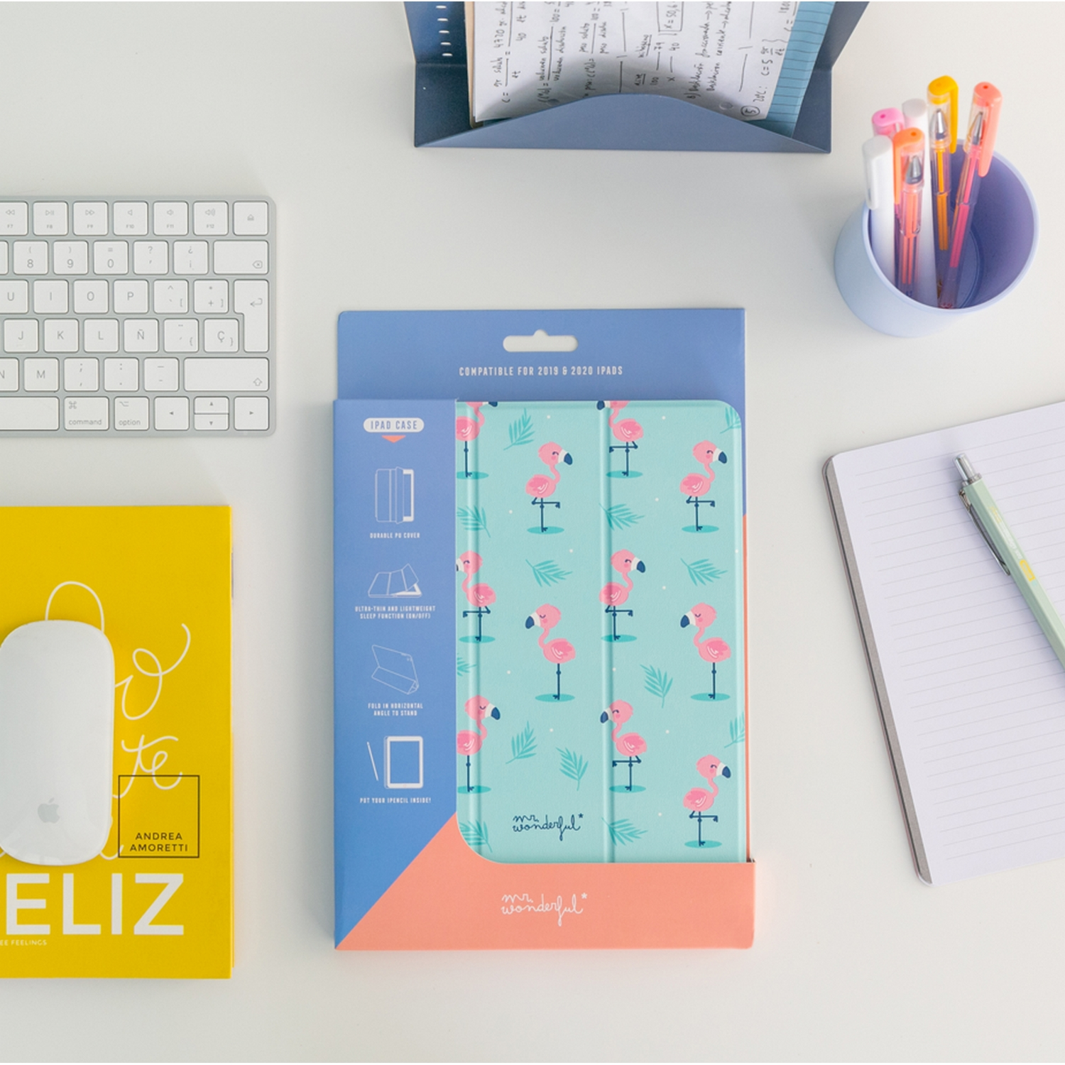 Funda para iPad con diseño de flamenco abierta sobre mesa con teclado, ratón, libreta y bolígrafos.