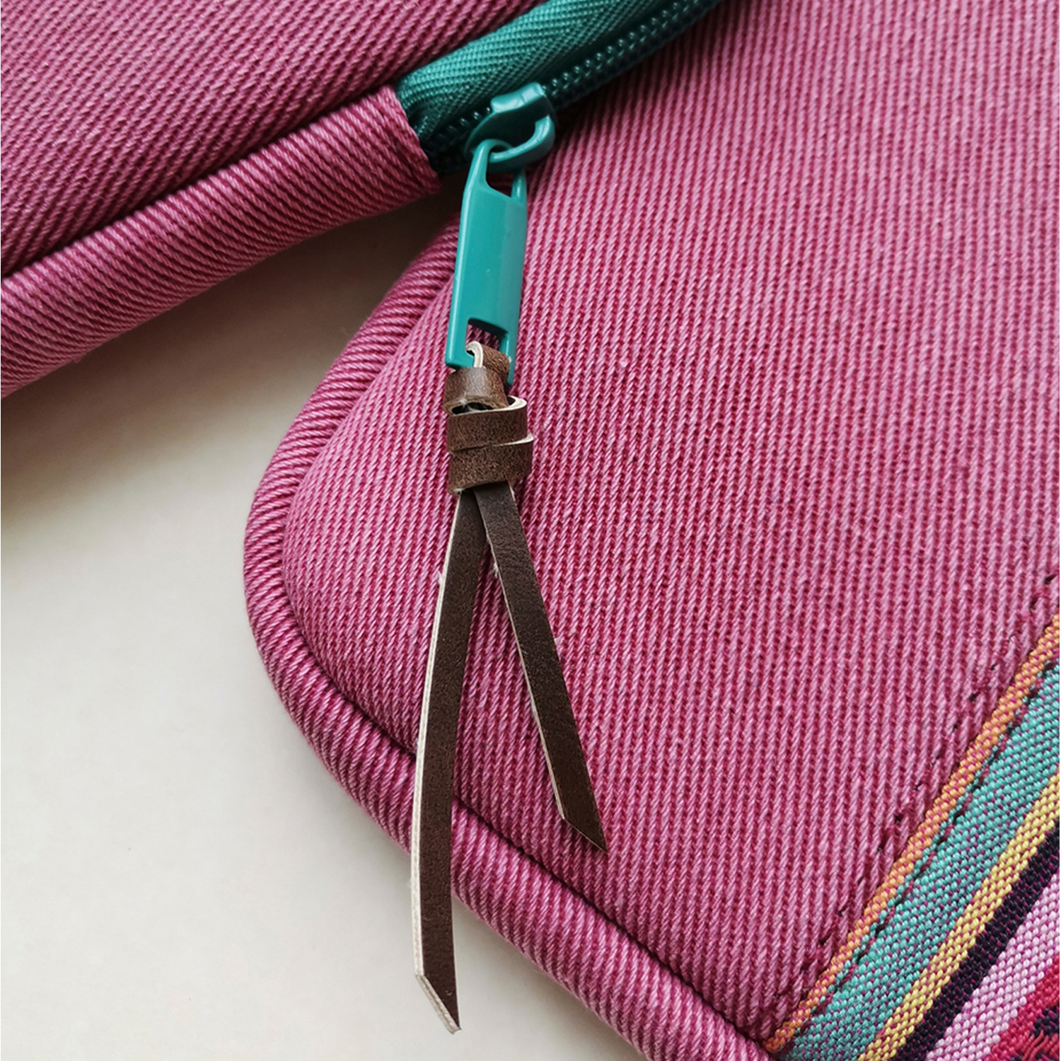Primer plano de un estuche rosa con cremallera, cremallera verde y tirador de cuero.