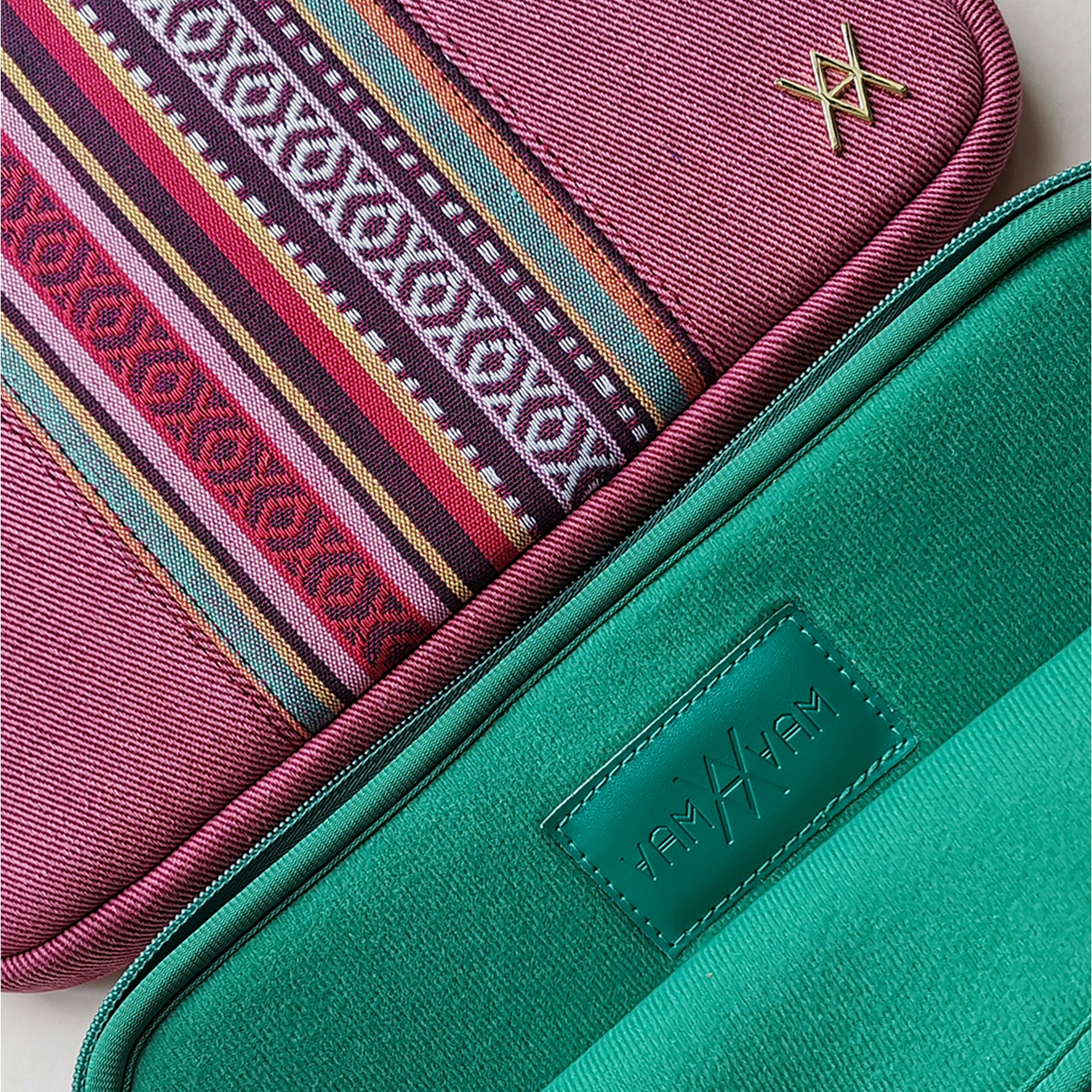 Primer plano de dos fundas para portátil: una rosa con un patrón, la otra verde con un logotipo.