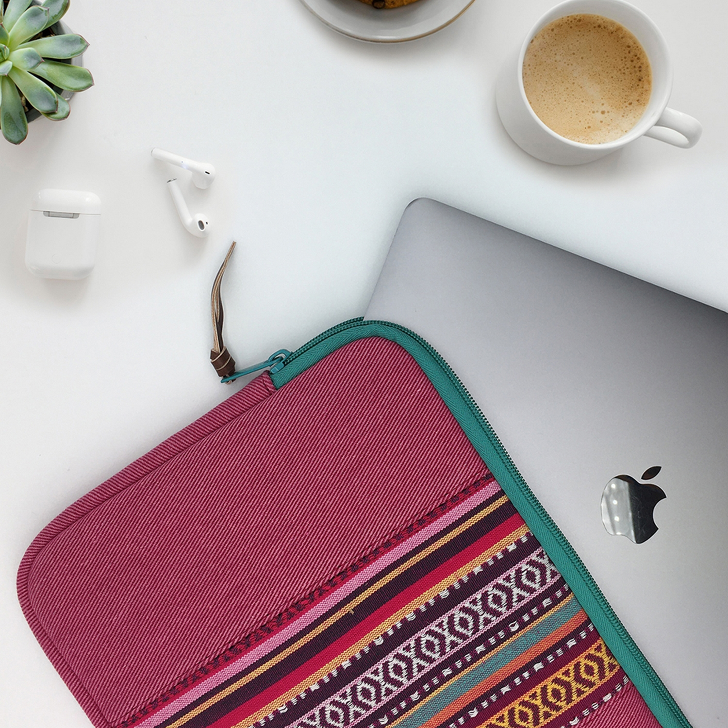 Laptop, funda, suculenta, café y auriculares.