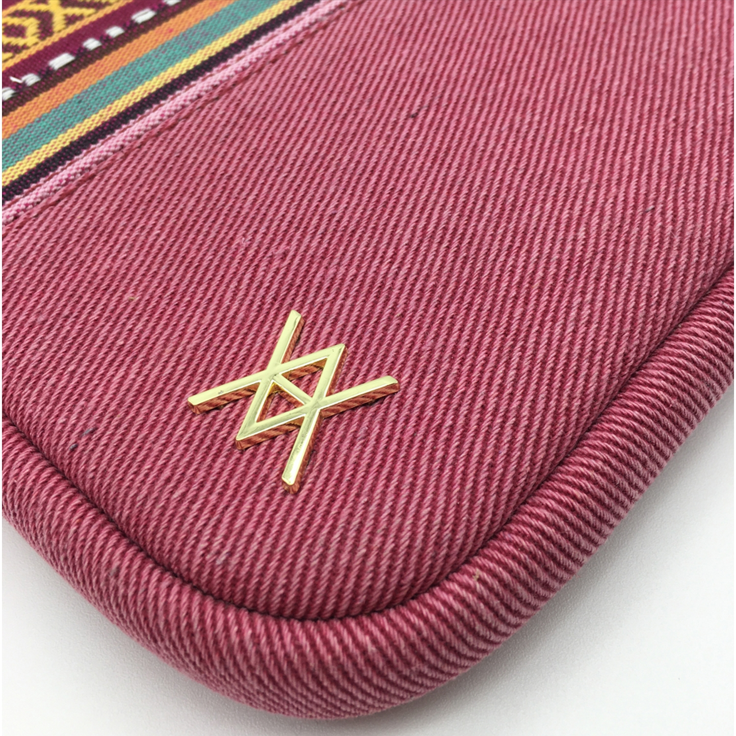 Primer plano de una almohadilla de mezclilla roja con un logotipo dorado y borde de tela colorida.