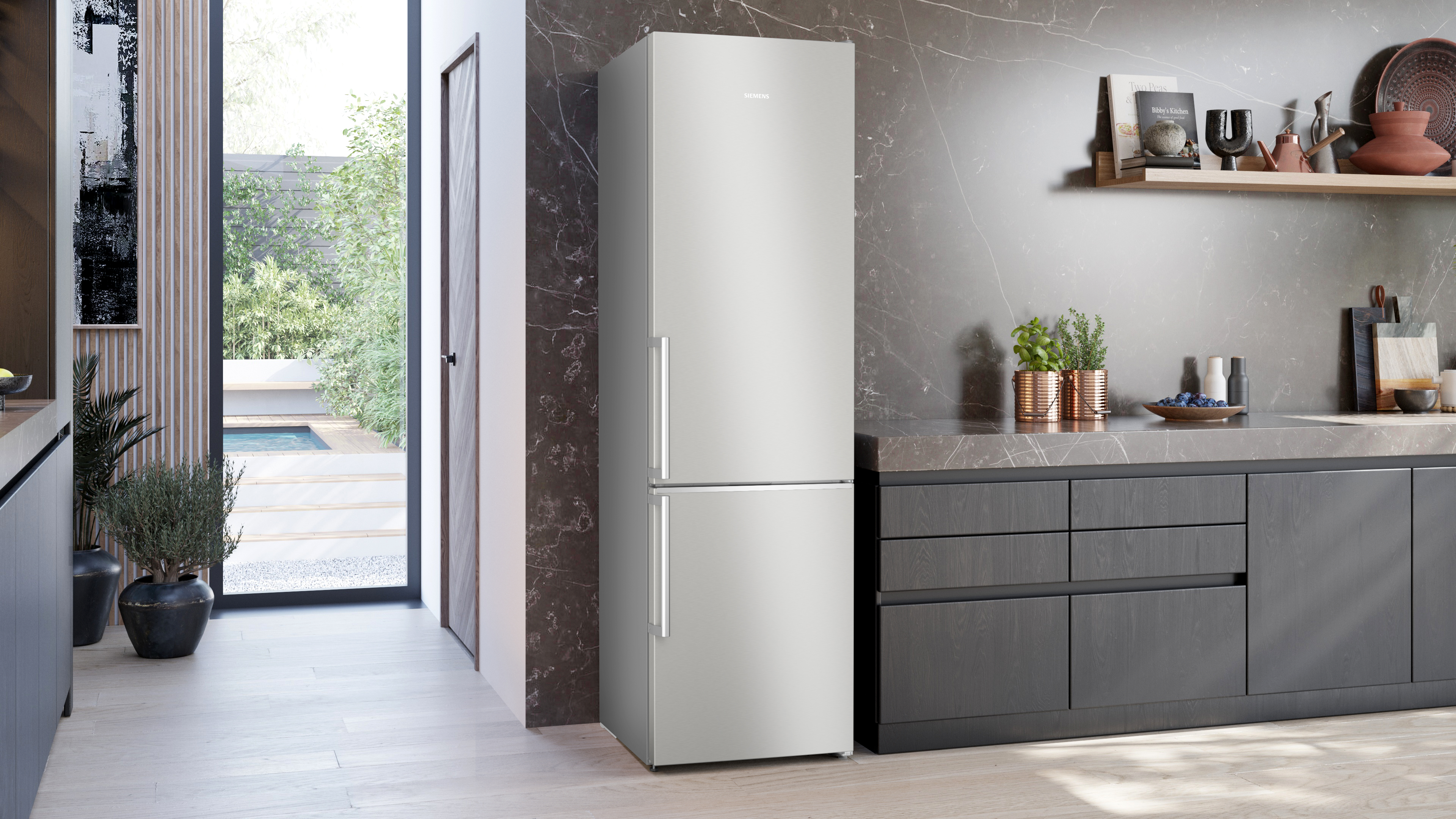 Eine moderne Küche mit einem silbernen Kühlschrank, einer dunklen Arbeitsplatte und Blick nach draußen.