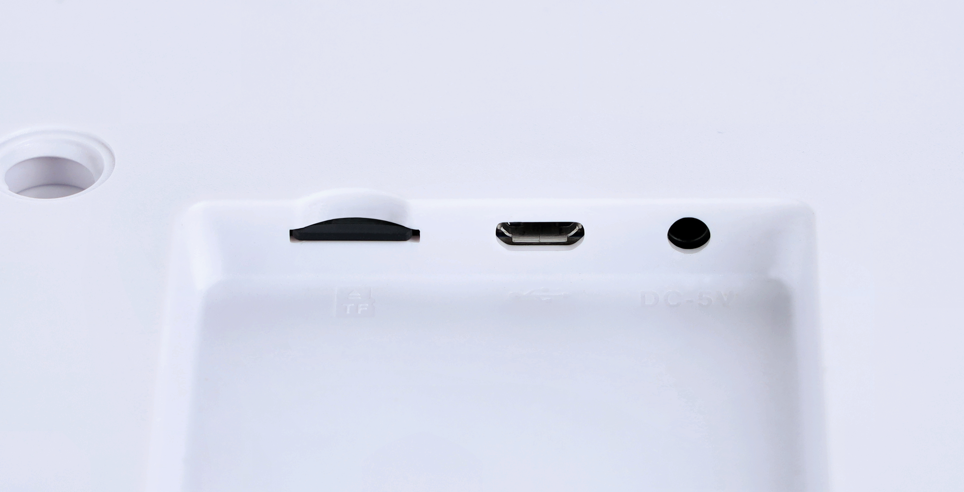 Nahaufnahme eines weißen Geräts mit mehreren Anschlüssen: TF-Karte, USB und DC 5V. Das Gerät vor weißem Hintergrund.