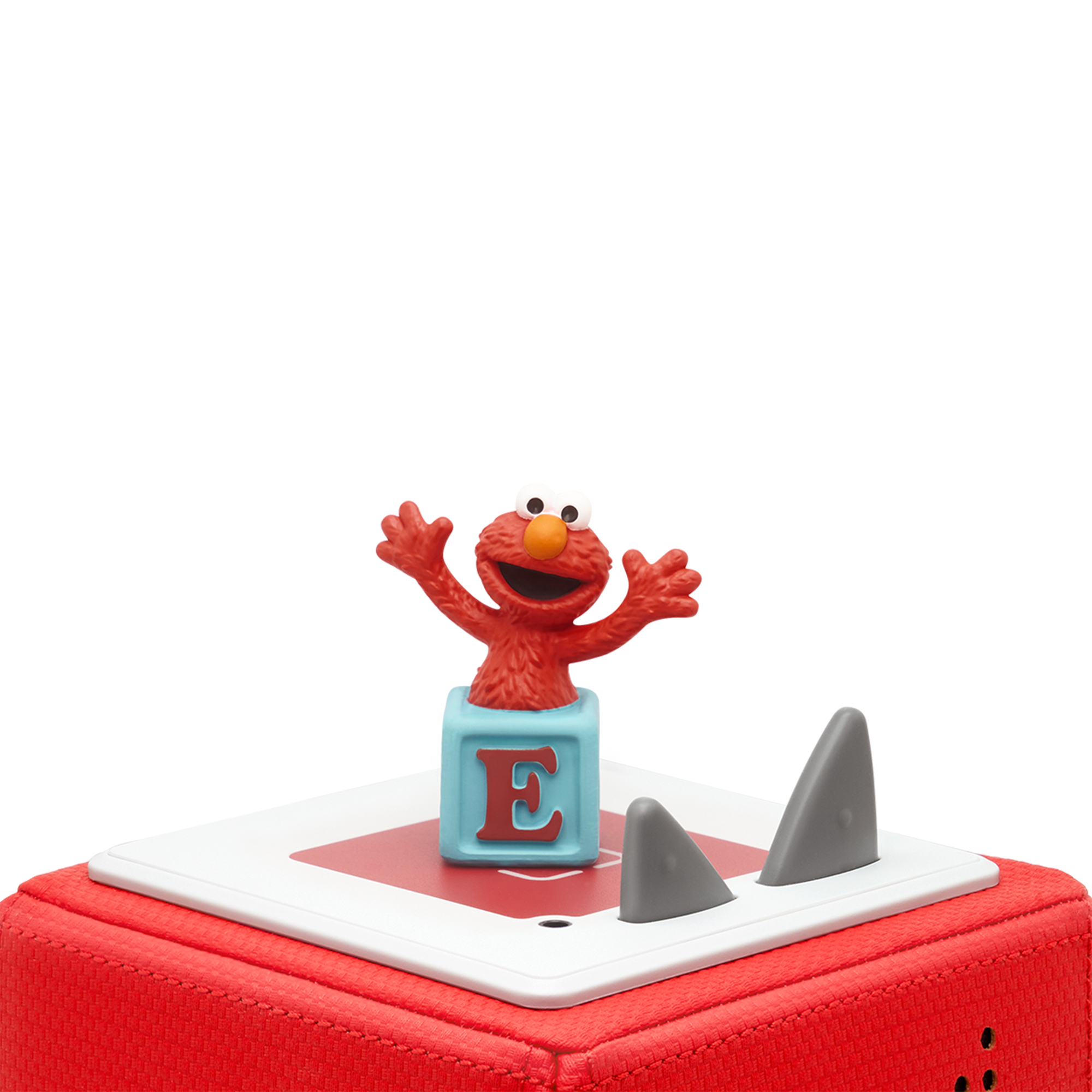 Elmo-Figur auf roter Box mit 'E' und Haifischflossen.