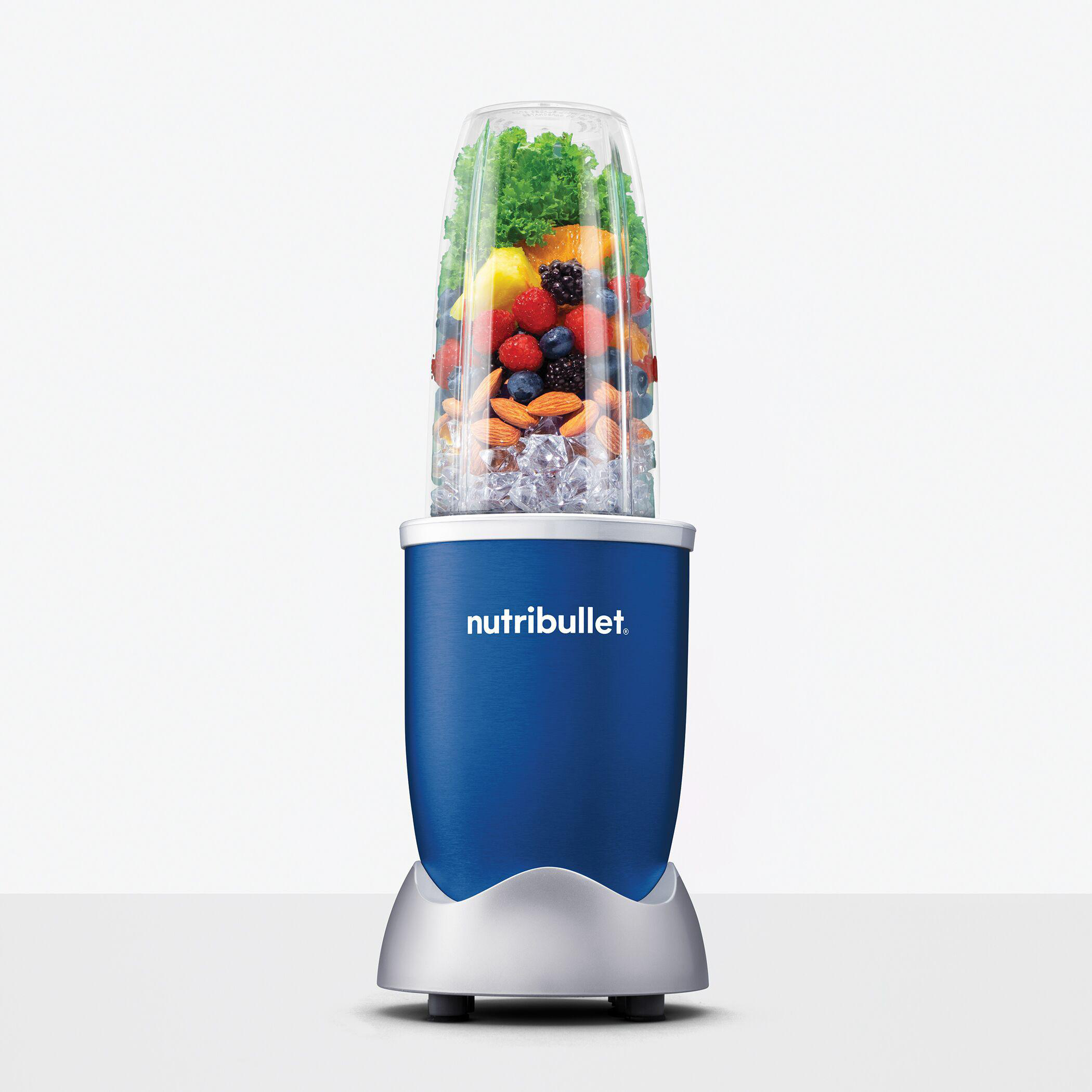 Nutribullet-Mixer mit blauem Sockel, gefüllt mit Früchten, Eis und Nüssen. Vor weißem Hintergrund.