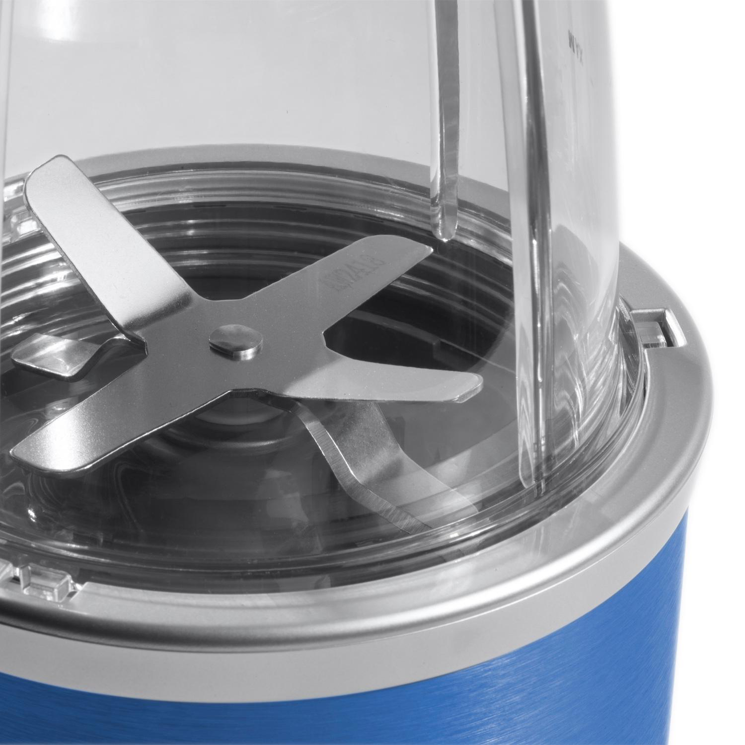 Nahaufnahme der Klingenanordnung eines Mixers. Silberklingen in einem transparenten Behälter, blauer Sockel. Metallischer Rand.